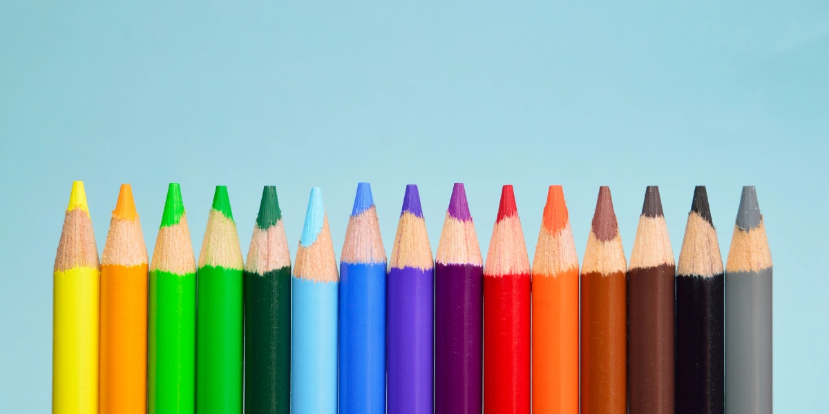 fifteen coloured pencils, lead facing up, are positioned on a blue background