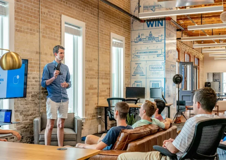a man giving a presentation to a group of people in an modern office setting