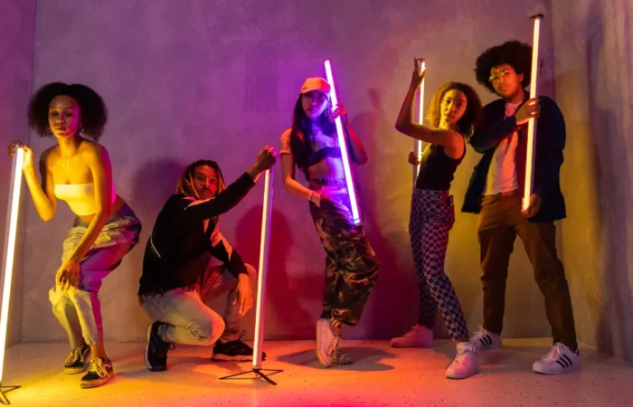 A group of young adults holding neon lights in a darkened room