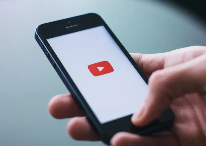 A person holding a phone that shows the YouTube logo