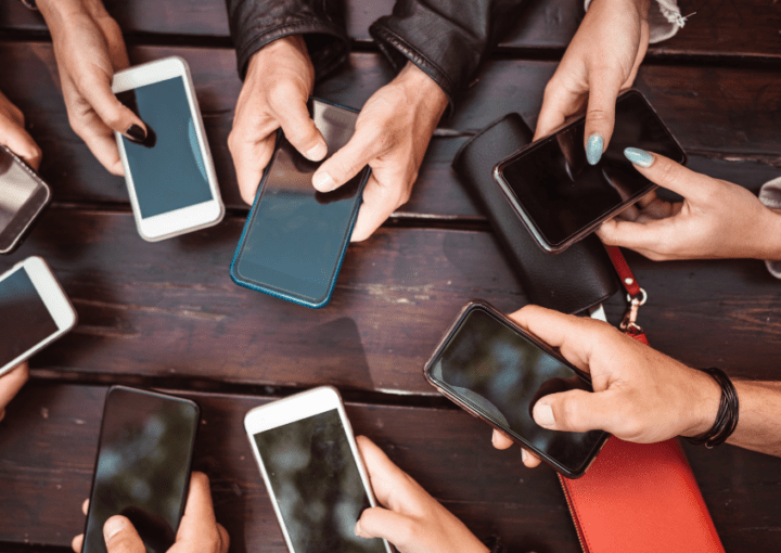 a group of people using phones against a dark wood table