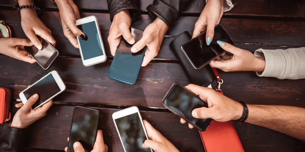 a group of people using phones against a dark wood table